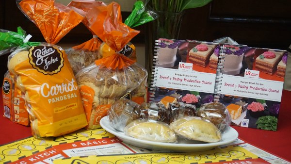 Baker John sliced breads and carrot pandesal - delicious bread made with URC Flour. In photo also were the recipe book and other bread and pastries served during the launch